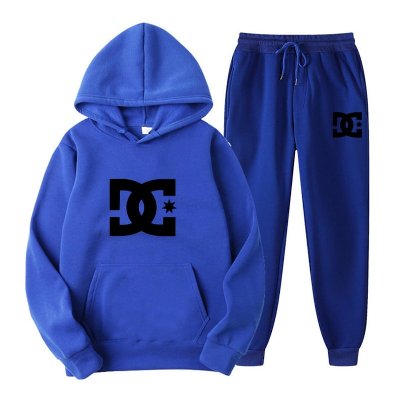 Peut inclure: Un ensemble bleu compos&eacute; d'un sweat &agrave; capuche et d'un pantalon de surv&ecirc;tement assorti. Le sweat &agrave; capuche a une poche avant et une capuche. Les deux pi&egrave;ces pr&eacute;sentent un logo noir sur le devant. Le pantalon de surv&ecirc;tement a une taille &agrave; cordon.
