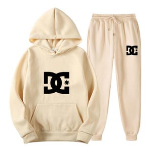 Peut inclure: Un ensemble de sweat &agrave; capuche et de pantalon de jogging beiges. Le sweat &agrave; capuche a une poche avant et une capuche &agrave; cordon. Les deux pi&egrave;ces pr&eacute;sentent un grand logo noir. Le pantalon de jogging a une taille &agrave; cordon et un logo sur la jambe gauche.
