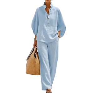 May include: A light blue two-piece set consisting of a long-sleeved shirt with a stand collar, a partial button-down front, and wide-leg trousers. The shirt features loose, flowing sleeves, and the trousers have a straight-leg cut.