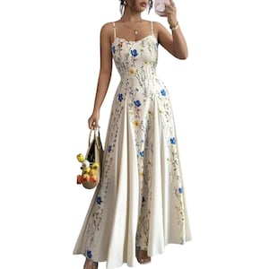 May include: A floor-length cream-colored dress featuring a delicate floral print with blue and yellow wildflowers. The garment has thin spaghetti straps, a fitted bodice, and a flared skirt that flows to the floor, creating a long silhouette.