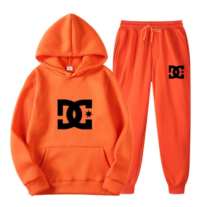 Peut inclure: Ensemble orange compos&eacute; d'un sweat &agrave; capuche et d'un pantalon de surv&ecirc;tement. Le sweat &agrave; capuche a un cordon de serrage et une poche kangourou. Les deux pi&egrave;ces pr&eacute;sentent un logo noir sur le devant.