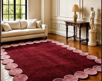 May include: A rectangular area rug featuring a deep burgundy center and a border composed of overlapping circular patches in varying shades of dusty pink and mauve, creating a scalloped edge effect across the entire perimeter.