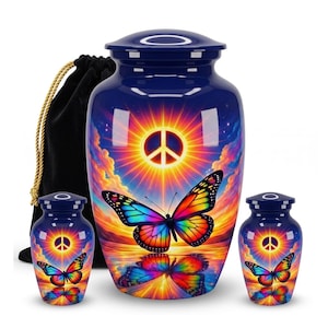 May include: A large dark blue cremation urn and two smaller matching keepsake urns, each featuring a vibrant, colourful butterfly and a glowing peace sign symbol against a sunset sky, accompanied by a black velvet drawstring bag.