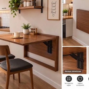 May include: A wall-mounted, foldable wooden table with a dark brown finish, featuring a black metal hinge mechanism that allows the surface to fold flat against the wall. Two wooden chairs with dark gray upholstered seats accompany the table.