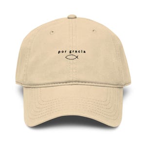 Peut inclure: Casquette de baseball beige avec l'inscription "por gracia" et un symbole de poisson noir. La casquette a une visière incurvée et une sangle réglable. Fabriquée en tissu doux et durable.