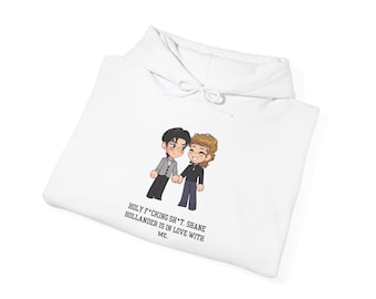 May include: White hoodie featuring a cartoon illustration of two figures holding hands. The text "HOLY F*CKING SH*T. SHANE HOLLANDER IS IN LOVE WITH ME." is printed below the illustration. The hoodie has a drawstring hood.