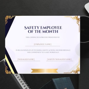 May include: A certificate for "Safety Employee of the Month" with gold and navy blue accents. The certificate includes fields for the employee and manager names, and the date. The text reads "Safety Employee of the Month".