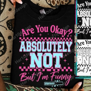 Op de afbeelding: Zwart sweatshirt met de tekst "Are You Okay? Absolutely Not, But I'm Funny" in roze en lichtblauw. Het ontwerp bevat een dambordpatroon en sterren.