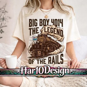 May include: Cream-colored t-shirt featuring a brown illustration of a steam train with the text "BIG BOY 4014 THE LEGEND OF THE RAILS". The shirt also includes the text "Har10Design".