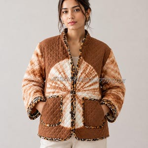 Peut inclure: Une veste matelassée avec un motif tie-dye brun et blanc en forme de soleil, des manches longues et deux poches avant. Le vêtement est bordé d'un imprimé léopard sur le col, l'ouverture avant, les poignets et les poches, avec des boutons.