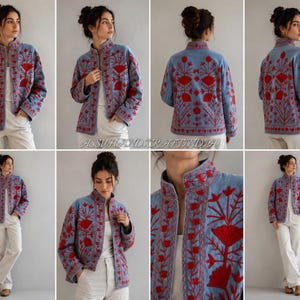 May include: A light blue jacket featuring intricate red floral embroidery throughout the front, back, and sleeves. The jacket has a high collar, long sleeves, and a straight hemline, worn over a white top and white trousers.
