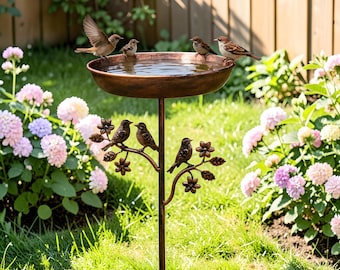 Könnte beinhalten: Ein bronzefarbenes Vogelbad mit einem dekorativen baumartigen Ständer. Mehrere kleine Vögel sitzen am Rand und im Wasser. Der Ständer hat dekorative Vögel und florale Akzente. Das Vogelbad befindet sich in einem Garten mit Blumen und Gras.