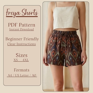 May include: The image shows a woman wearing a cream-colored crop top and brown patterned shorts. The shorts have a drawstring waist and a repeating design in shades of brown, blue, and orange. Text on the left side reads "Freya Shorts" and details about the PDF pattern.