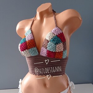 May include: A multi-colored crochet bikini top with a halter style neckline. The top is made with a patchwork design of squares in shades of brown, pink, teal, orange, and cream. The top has a brown trim and is tied at the neck and back. The text "@NZLDESIGNN" is printed on the bottom of the top.