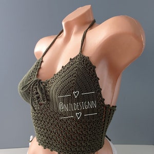 Pu&ograve; includere: Un top halter in crochet verde con un motivo delicato. Il top &egrave; legato al collo e alla schiena. Il top &egrave; mostrato su un manichino. Il testo "@NZLDESIGNN" &egrave; scritto sul top.