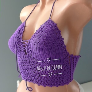 Pu&ograve; includere: Top halter in crochet viola con un laccio sul davanti. Il top &egrave; su un manichino e ha il testo "@NZLDESIGNN" su di esso.