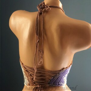 Pu&ograve; includere: Un top halter lavorato a uncinetto con uno schema di colori marrone e viola. Il top ha una schiena con lacci e &egrave; realizzato con un filato testurizzato.