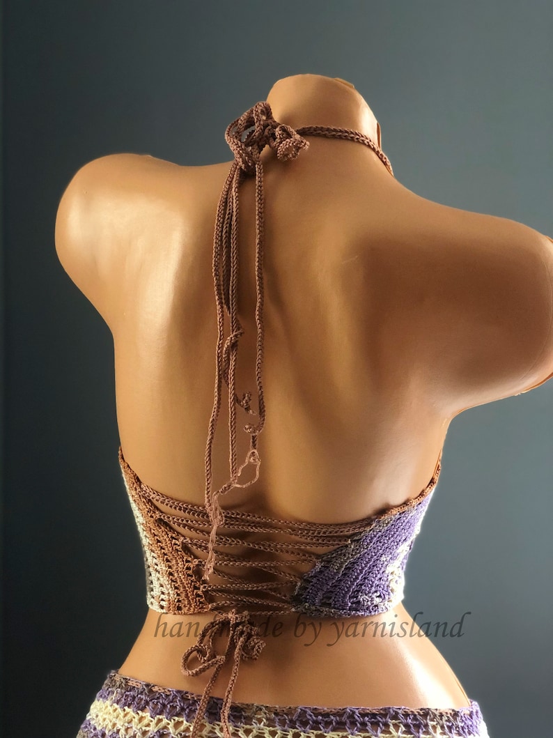 Pu&ograve; includere: Un top halter lavorato a uncinetto con uno schema di colori marrone e viola. Il top ha una schiena con lacci e &egrave; realizzato con un filato testurizzato.
