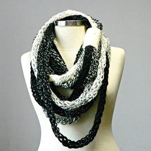 May include: A black and white infinity scarf with a gradient pattern. The scarf is made of soft yarn and is perfect for keeping warm in the winter.