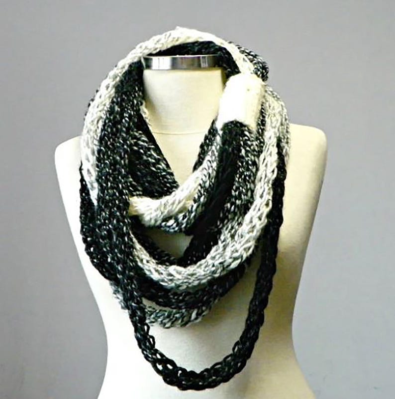 May include: A black and white infinity scarf with a gradient pattern. The scarf is made of soft yarn and is perfect for keeping warm in the winter.