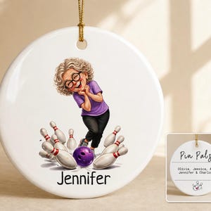 May include: A round white ceramic ornament featuring a cartoon illustration of a person with curly gray hair and glasses wearing a purple shirt and black pants, bowling with a purple ball and white pins. The name Jennifer is printed below.