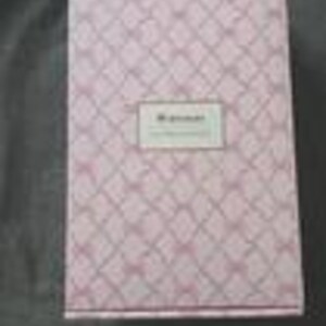 May include: A rectangular pink box with a diamond pattern and a white label in the center. The label has the text "My Journal" in a serif font. The box is closed and appears to be made of cardboard.
