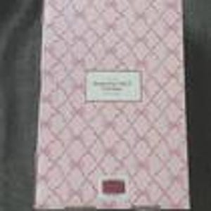 May include: A pink and white patterned box with the text "Something Nice" in a rectangular label. The box has a diamond pattern and a small rectangular label at the bottom. The box is closed.
