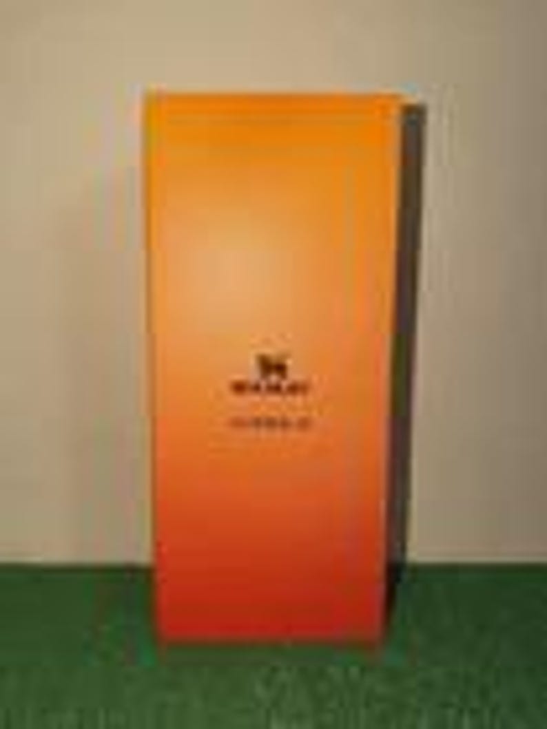 May include: A rectangular box with a vertical gradient transitioning from yellow at the top to orange at the bottom. The center features a black logo of a stylized animal silhouette above the text WAKAY and the word ESSENTIALS in black.