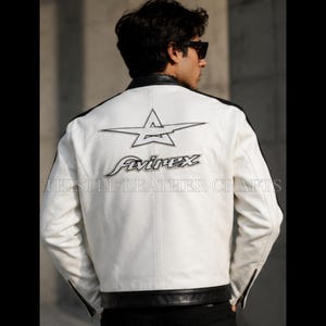 May include: White leather jacket with black accents on the shoulders and hem. Features a star logo and the "Avirex" brand name in black on the back. The jacket has a classic motorcycle style with a zipper closure.