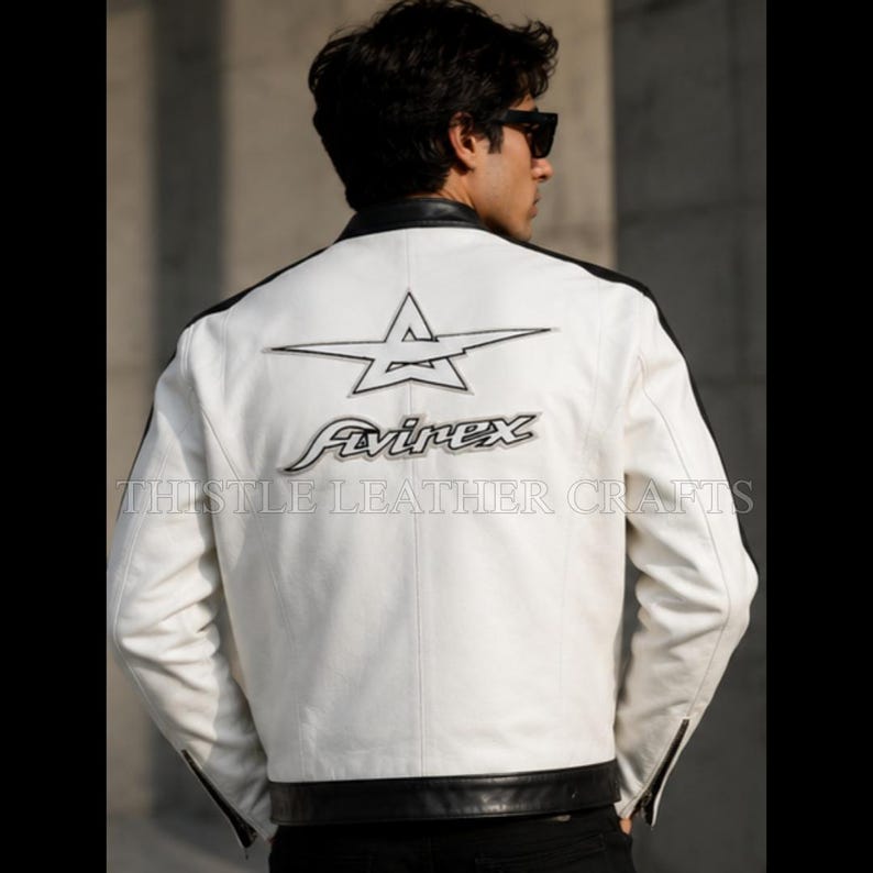 May include: White leather jacket with black accents on the shoulders and hem. Features a star logo and the "Avirex" brand name in black on the back. The jacket has a classic motorcycle style with a zipper closure.