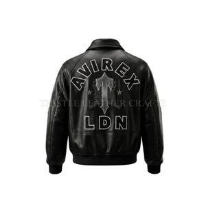 Könnte beinhalten: Schwarze Leder-Bomberjacke mit Kragen und gerippten Bündchen. Auf dem Rücken befindet sich ein weiß gestickter Text mit der Aufschrift "AVIREX LDN" mit einem Logo in der Mitte. Klassische Jacke.