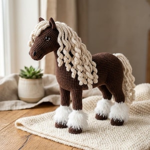 May include: A handcrafted crochet horse figurine. The horse is primarily brown with a cream-colored mane and tail. The hooves are adorned with fluffy white accents. The horse is posed on a cream-colored, textured surface.