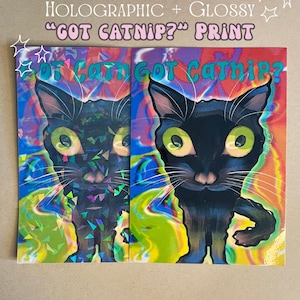 May include: Two glossy prints featuring a black cat with large green eyes and the text "GOT CATNIP?". The prints are 7" x 5" and have a holographic effect. The background is a mix of bright colors.