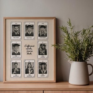 May include: A wooden framed print displaying black and white photographs of people in graduation gowns, styled as tarot cards. The text "Different cards, Same deck" is in the center. A vase with greenery sits on a wooden surface.