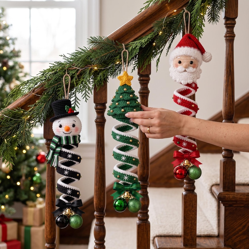 May include: Three crocheted Christmas ornaments hanging from a wooden banister. One is a snowman with a black hat, one is a green Christmas tree with a yellow star, and one is a Santa Claus. Each features a spiral body with small ornaments.