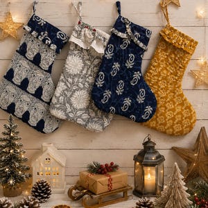 Könnte beinhalten: Vier gesteppte Weihnachtsstrümpfe hängen in einer Reihe. Der erste ist marineblau mit weißem Gesichtsmuster, der zweite grau mit Blumenmuster, der dritte marineblau mit weißem Paisleymuster und der vierte senfgelb mit weißem Blumenmuster.