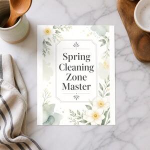 May include: A rectangular paper sign featuring the text Spring Cleaning Zone Master in dark gray font, framed by a decorative border of watercolor-style white flowers, green leaves, and soft sage green paint splatters on a white background.