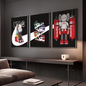 May include: Three framed art prints featuring pop art designs. One print shows a figure with hands covering its face, another displays stacked sneakers, and the third depicts a figure with boxing gloves and punching bags. All prints have a black background.