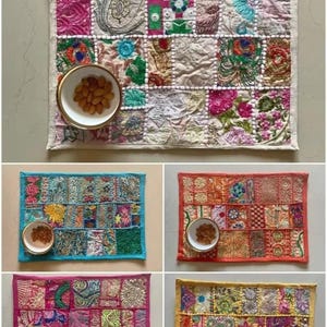 May include: A rectangular placemat featuring a patchwork of various embroidered fabric squares in vibrant colors, including pink, blue, orange, and yellow. Each placemat is bordered by a solid color trim and includes a small white bowl with nuts.