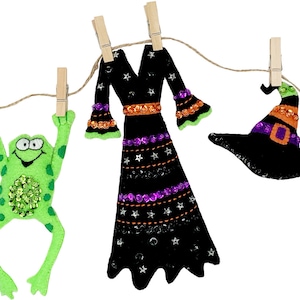 May include: A Halloween garland with a witch's dress, hat, frog, and broom hanging from clothespins on a string.