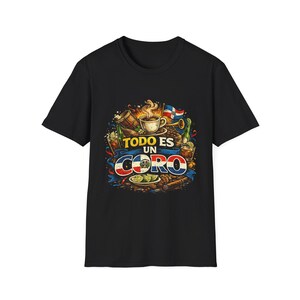May include: Black t-shirt featuring a colorful graphic design. The design includes a coffee cup, Dominican Republic flag, musical instruments, and the text "TODO ES UN CORO" in a stylized font. The design is surrounded by coffee beans and other elements.