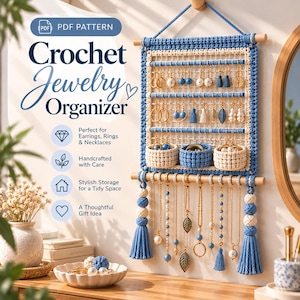 Peut inclure: Un organisateur de bijoux en crochet à suspendre, composé de fils bleus et crème, de tiges en bois et de pompons. Il comprend une grille pour les boucles d'oreilles, trois petits paniers pour les bagues et des crochets pour colliers. Texte : PDF PATTERN Crochet Jewelry Organizer.