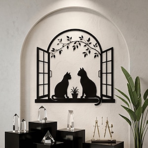 May include: A black metal wall art piece featuring a silhouette of two cats sitting on a window sill with an open window frame design. Above the cats, a curved archway is decorated with delicate leafy branches, and a small potted plant sits between them.