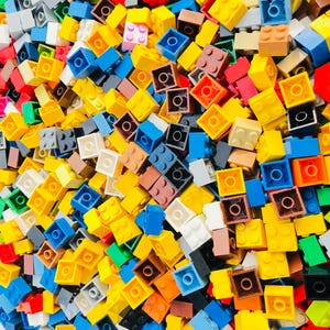 May include: A vibrant assortment of colorful toy building blocks. The blocks are in various colors, including yellow, blue, red, and brown. Each block has a circular hole on top and is designed to connect with others. The image is a close-up shot of the blocks.