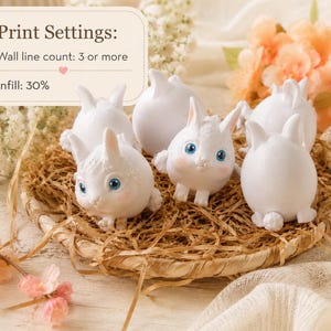 May include: A collection of white bunny figurines with blue eyes and pink accents, arranged in a woven basket filled with straw. The image includes text that says "Print Settings: Wall line count: 3 or more, Infill: 30%."