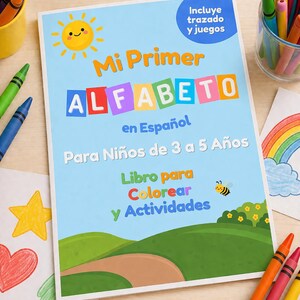 Op de afbeelding: Een Spaanstalig kinderactiviteitenboek getiteld "Mi Primer ALFABETO en Español" met een blauwe kaft. De kaft toont een lachende zon, kleurrijke letters en illustraties van een landschap en een bij. Kleurpotloden en tekeningen omringen het boek.