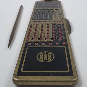 Pode incluir: Uma calculadora mecânica Addiator Universal vintage com caixa de metal dourado e painéis pretos. O dispositivo apresenta colunas de números para adição e subtração, com o texto "SALDO NEG." e um estilete incluído para operação.