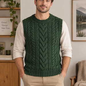 May include: A dark green cable knit sweater vest featuring a crew neckline and ribbed trim at the armholes and hem. The garment is worn over a long-sleeved light beige shirt and paired with khaki trousers, showcasing a textured vertical pattern.
