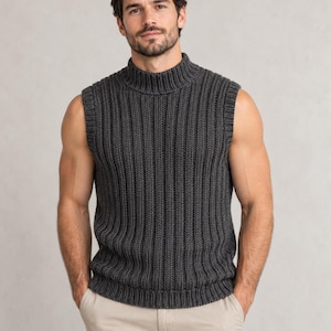 Könnte beinhalten: Eine dunkel anthrazitfarbene ärmellose Strickweste mit dicker Rippstrickstruktur, einem hohen Stehkragen und einem geraden Saum. Das Kleidungsstück ist mit einem vertikalen Rippenmuster über den gesamten Körper gearbeitet und mit Rippbündchen versehen.