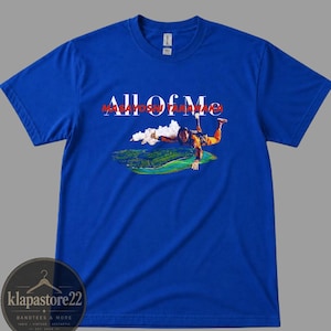 Könnte beinhalten: Königsblaues T-Shirt mit dem Text "ALL OF ME" in Weiß und Rot. Das Shirt hat eine Grafik einer Person, die über einer Landschaft Fallschirm springt. Das Shirt ist von klapastore22.
